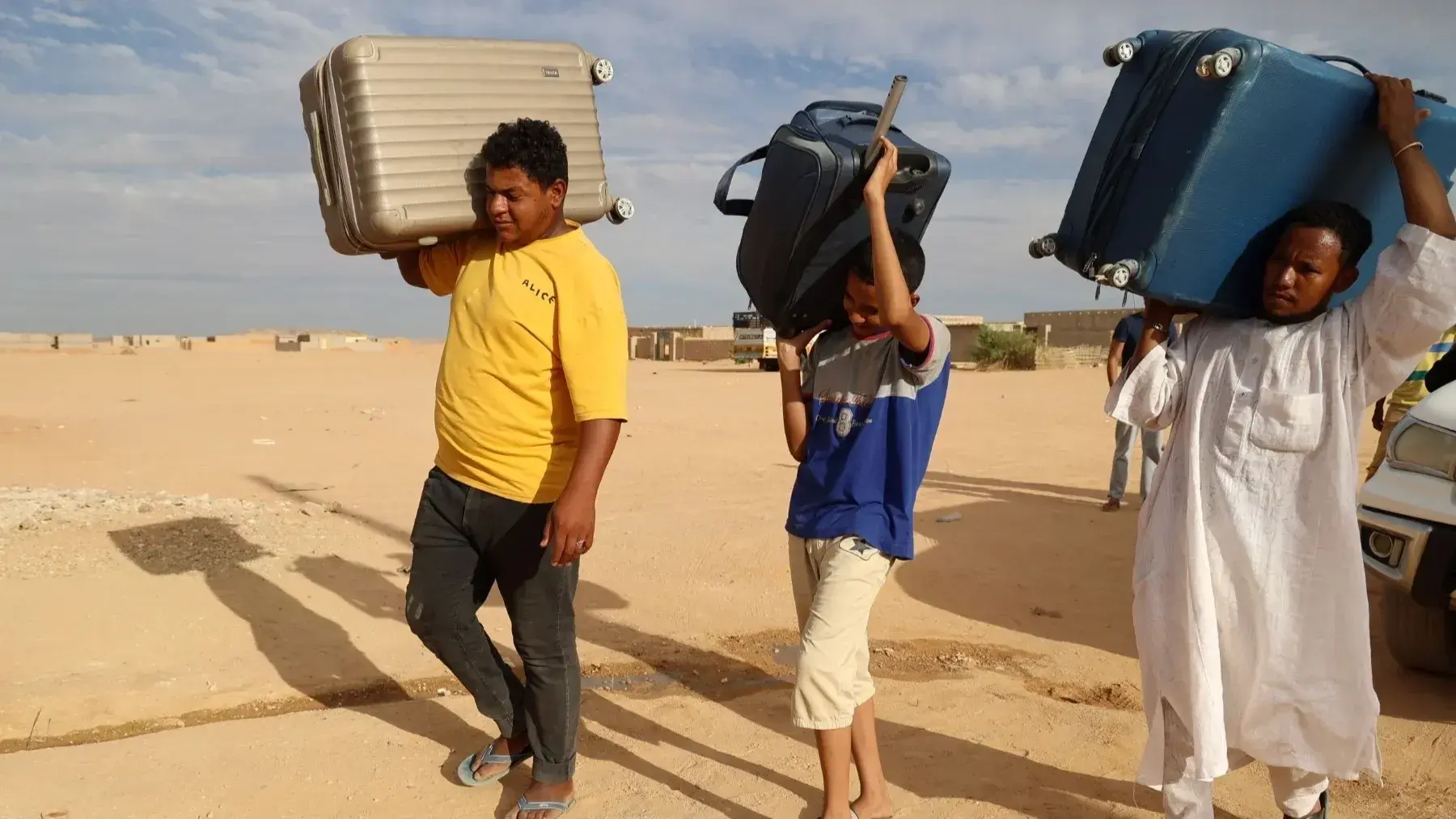 مجموعة شباب سودانيين يحملون شنط سفر في محطة مع جوازات السفر والحقائب في سياق شرح شروط الإقامة في مصر للسودانيين