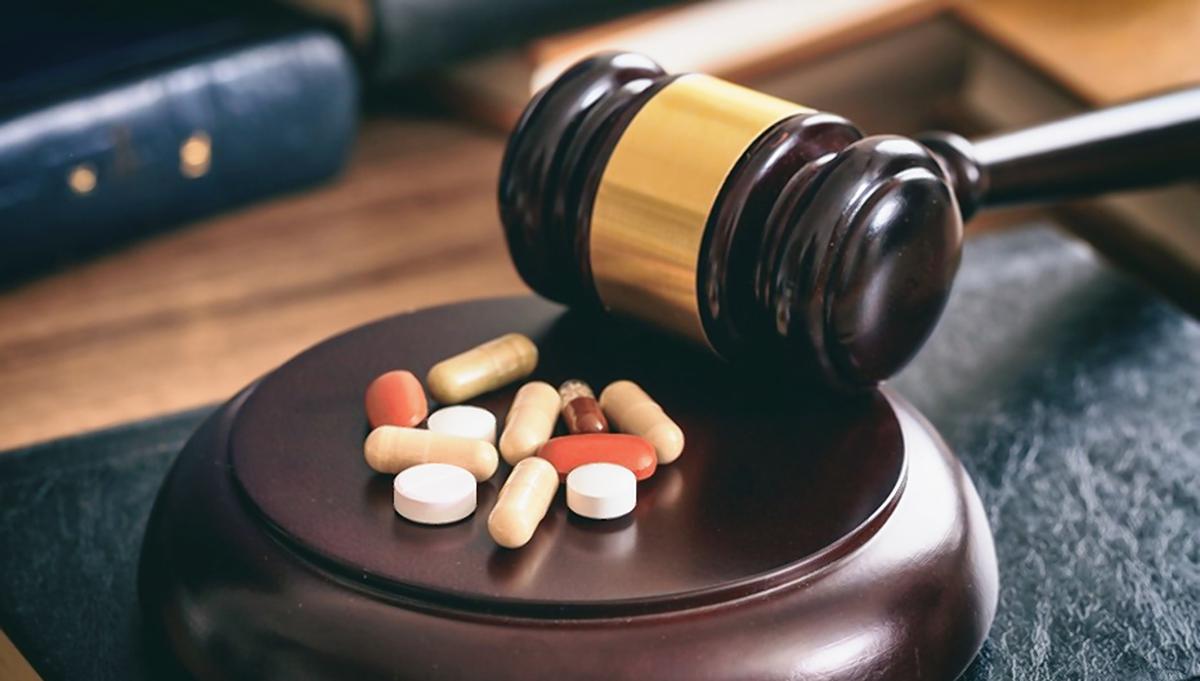 الدفوع في قضايا جلب المخدرات مضبوطات مواد مخدرة بجوار شاكوش قاض داخل قاعة المحكمة في قضية جلب مخدرات في مصر وتقييم الأدلة والإجراءات القانونية.