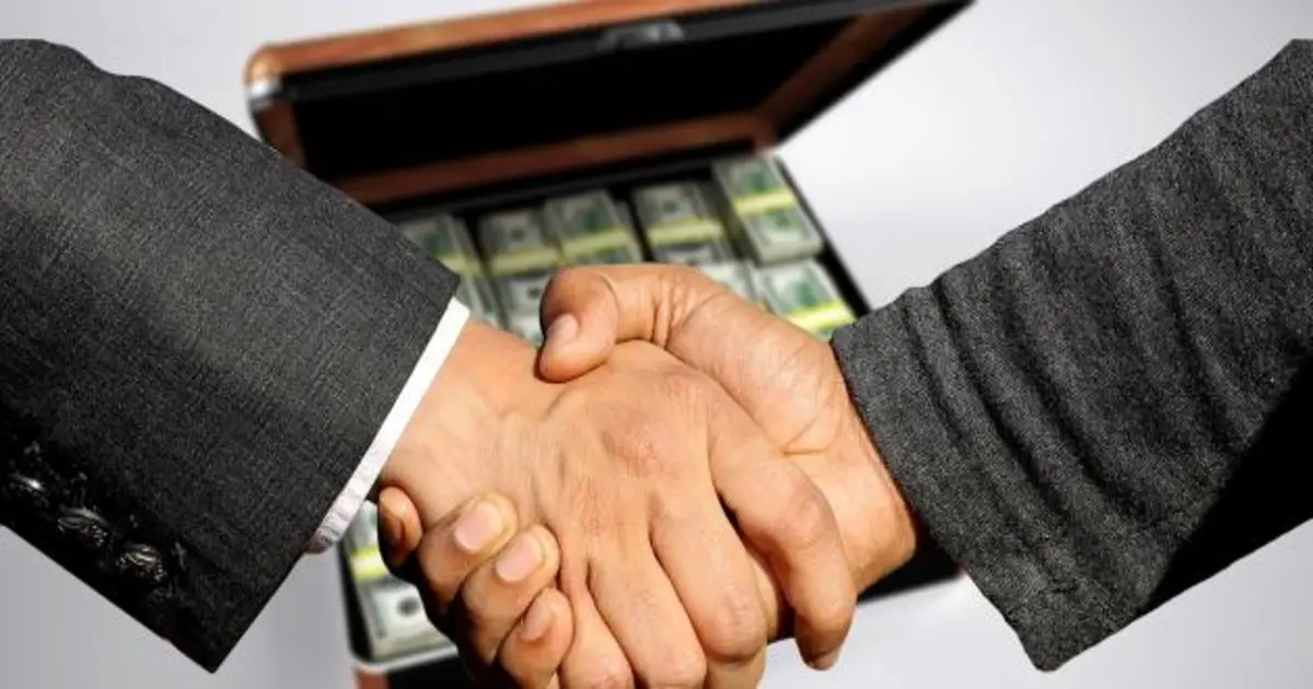 يدان تتصافحان فوق عقد بيع مع إشارة لإمكانية حبس الثمن عند الإخلال كأحد الحالات التي يحق للمشتري فيها حبس الثمن في عقد البيع وفقًا للقانون المصري.